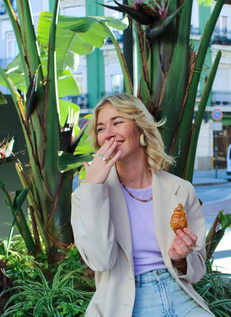 Lachende webdesigner die een croissant eet